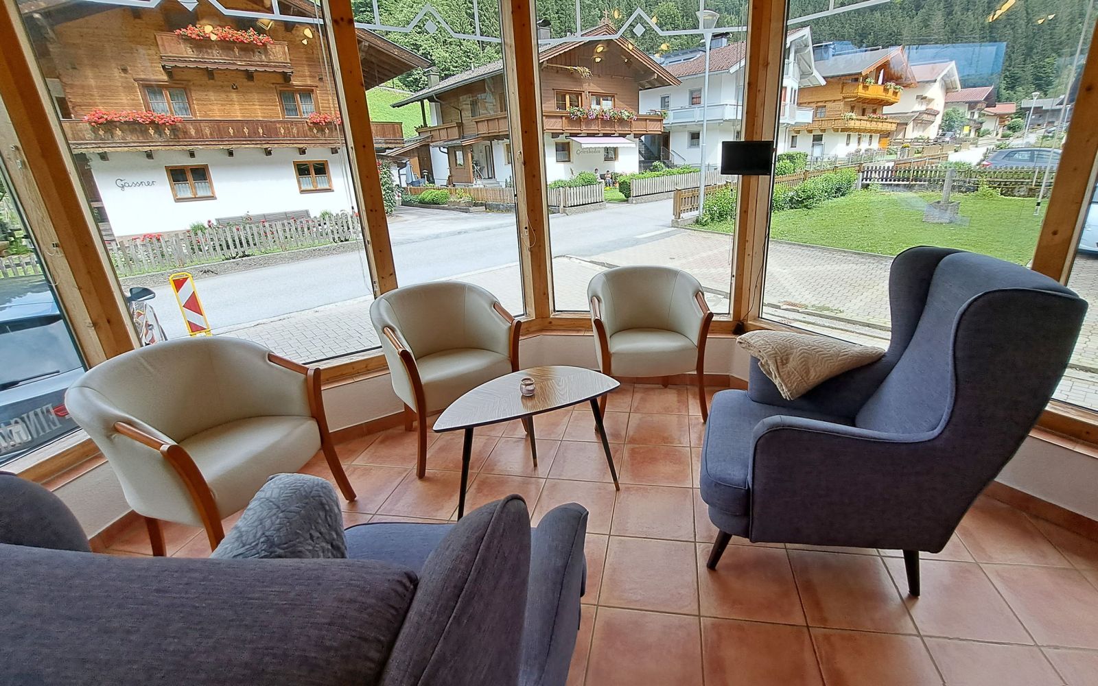Gemütlicher Wintergarten der Alpenland Appartements mit Sesseln und Blick auf das Dorf Auffach