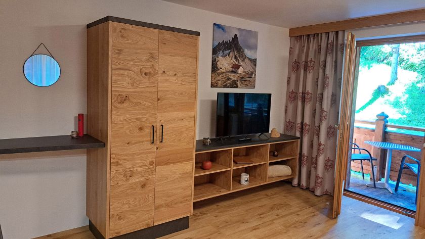 Wohnbereich im Appartement Gratlspitz mit TV, Schrank und Zugang zum Balkon