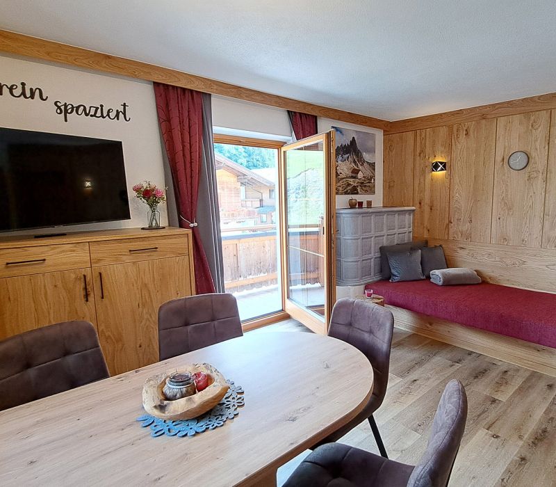 Heller Wohnbereich im Appartement Schönangeralm mit Esstisch, TV, Liege und Balkon