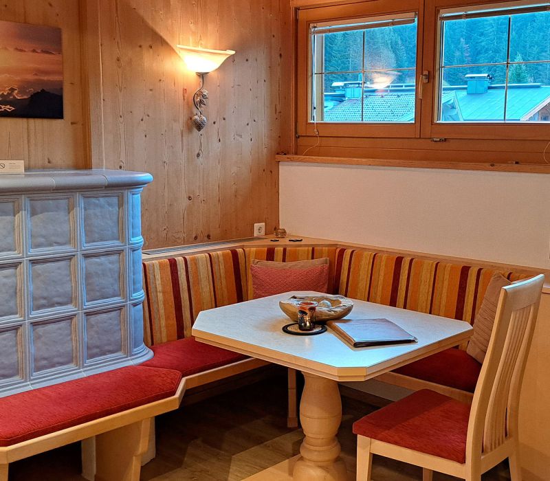 Essecke im Appartement Großer Beil mit Kachelofen, Holzverkleidung und TV