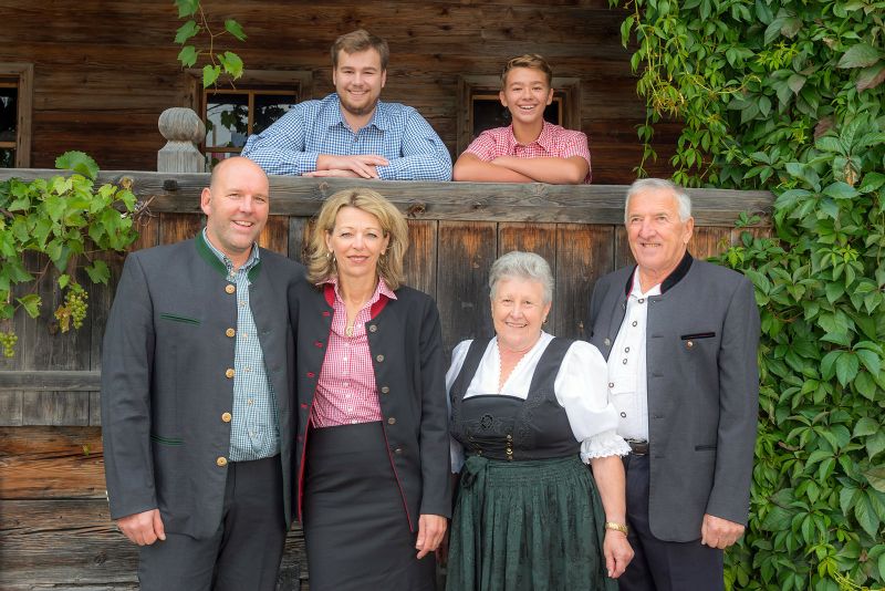 Gastgeberfamilie Fankhauser der Alpenland Appartements vor traditionellem Holzhaus in Tirol