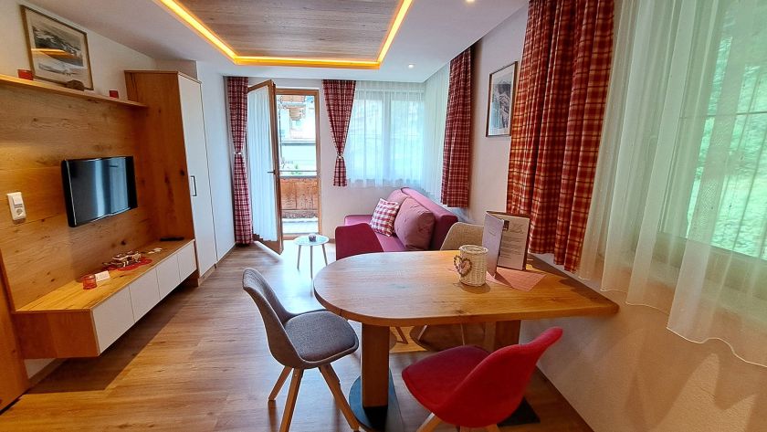 Wohnraum im Appartement Feldalphorn mit Esstisch, Sofa und Balkonzugang
