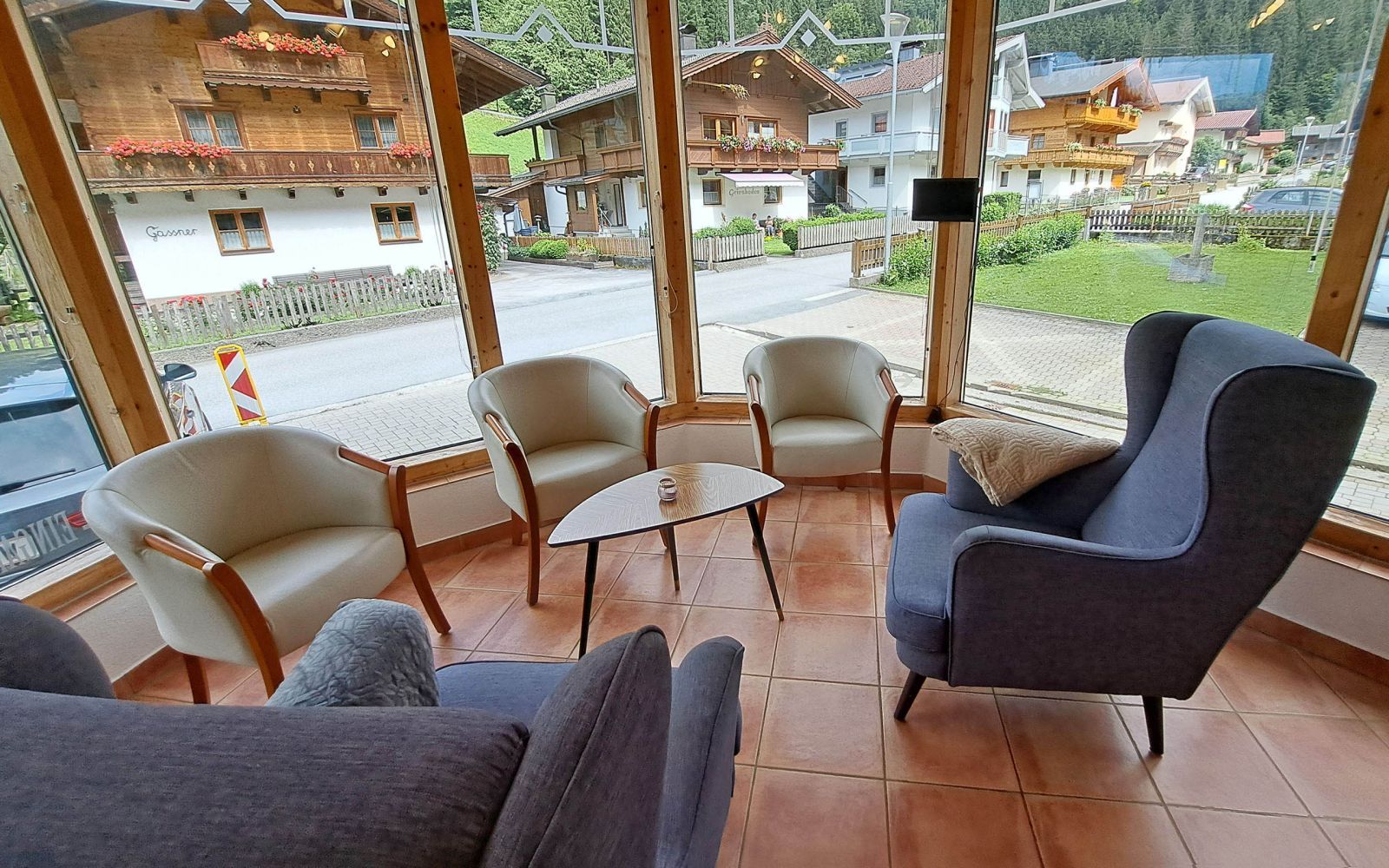 Gemütlicher Wintergarten der Alpenland Appartements mit Sesseln und Blick auf das Dorf Auffach