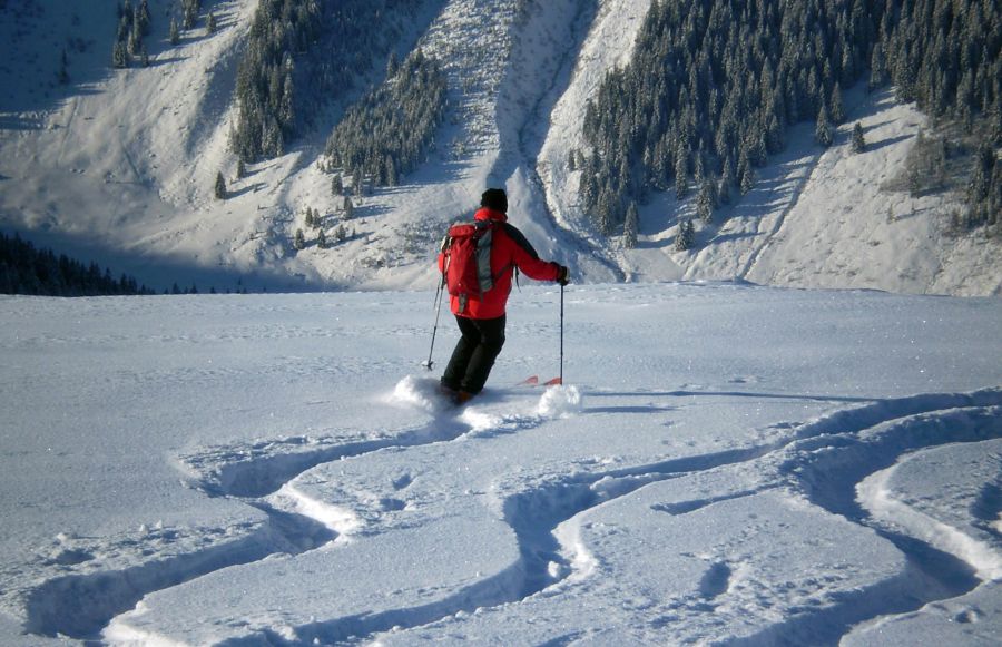 Skifahrer im Tiefschnee vor verschneiter Berglandschaft in Tirol