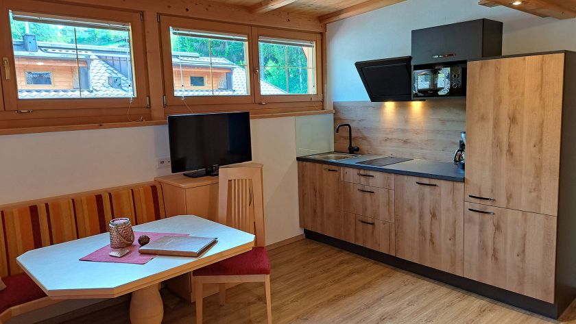 Küche mit Essecke und TV im Appartement Großer Beil in warmer Holzoptik