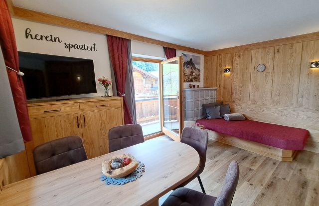Heller Wohnbereich im Appartement Schönangeralm mit Esstisch, TV, Liege und Balkon