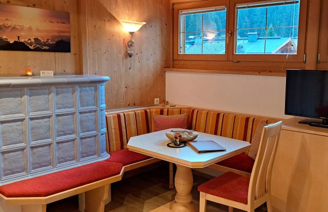 Essecke im Appartement Großer Beil mit Kachelofen, Holzverkleidung und TV