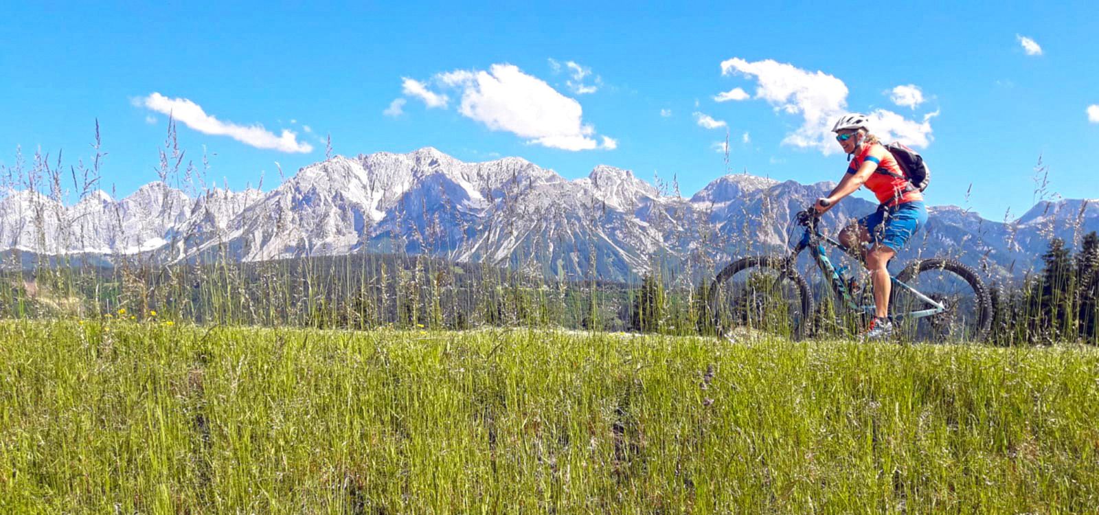 Mountainbikerin auf Almwiese vor eindrucksvoller Bergkulisse in Tirol