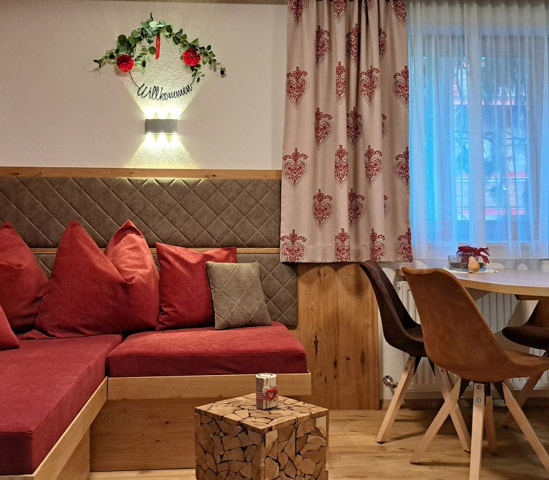 Gemütlicher Wohn- und Essbereich im Appartement Gratlspitz mit roter Sitzecke